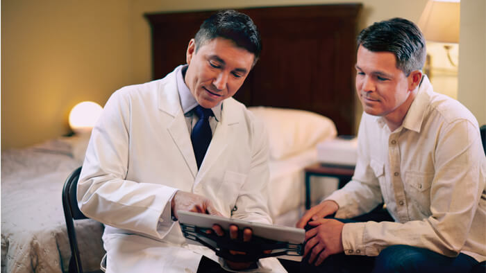 Foto på en läkare som visar en man resultat på en surfplatta