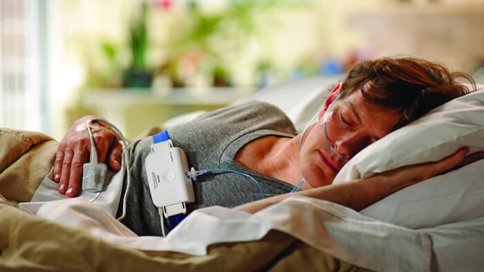 Foto på en man som ligger på sidan i sängen och sover med ett Philips-sömntest