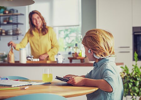 Pojke som tittar på en video samtidigt som han bär Philips open-ear-hörlurar för barn