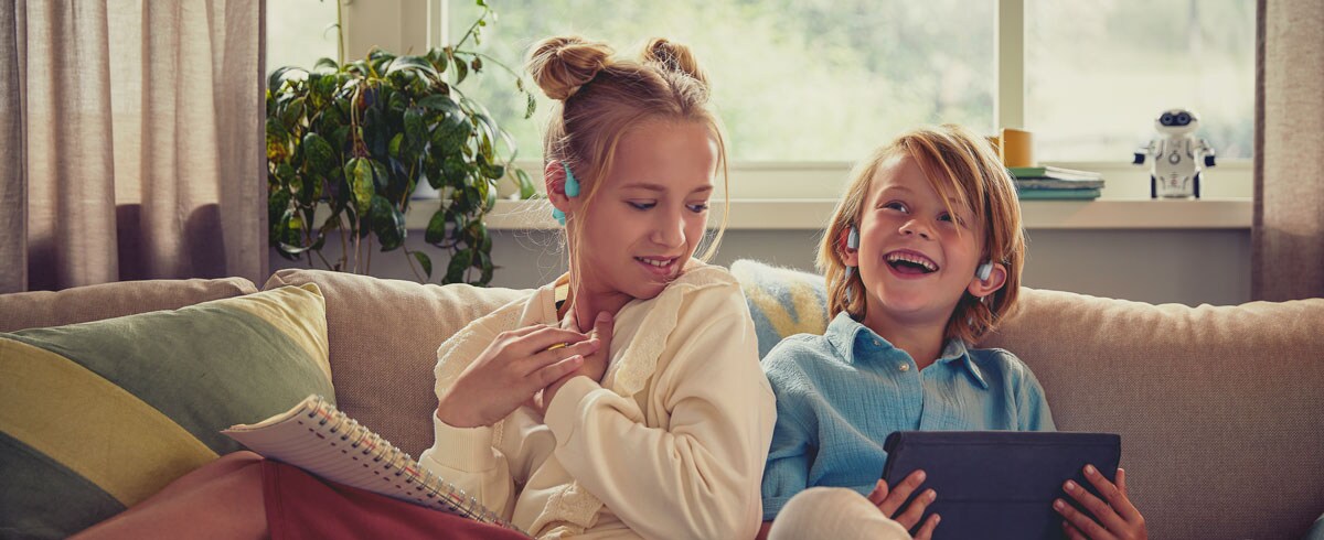Barn som tittar på en video med Philips open-ear-hörlurar för barn