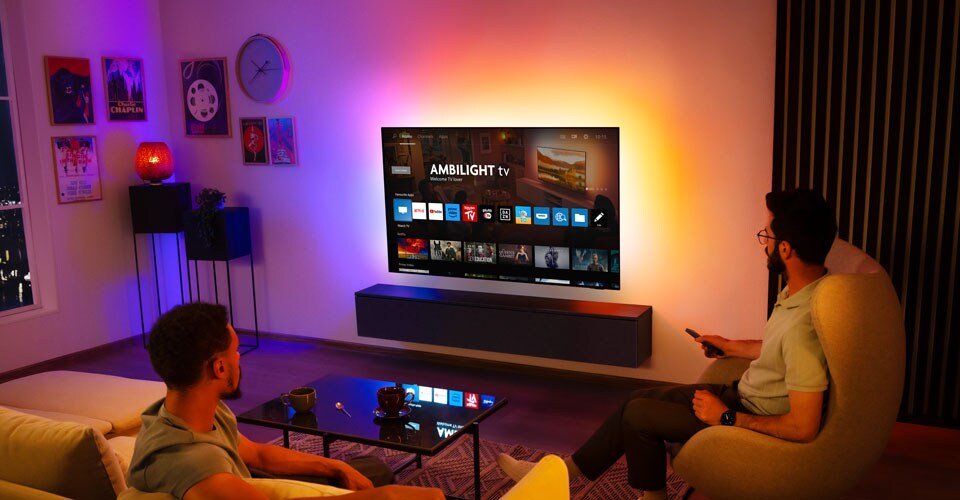 Två män tittar på en väggmonterad Ambilight-TV i ett vardagsrum