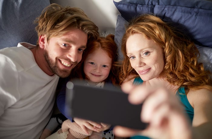 En kvinna tar en selfie med sin man och sin lilla dotter.