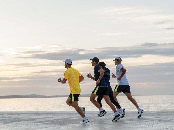 Fyra deltagare springer tillsammans på stranden.