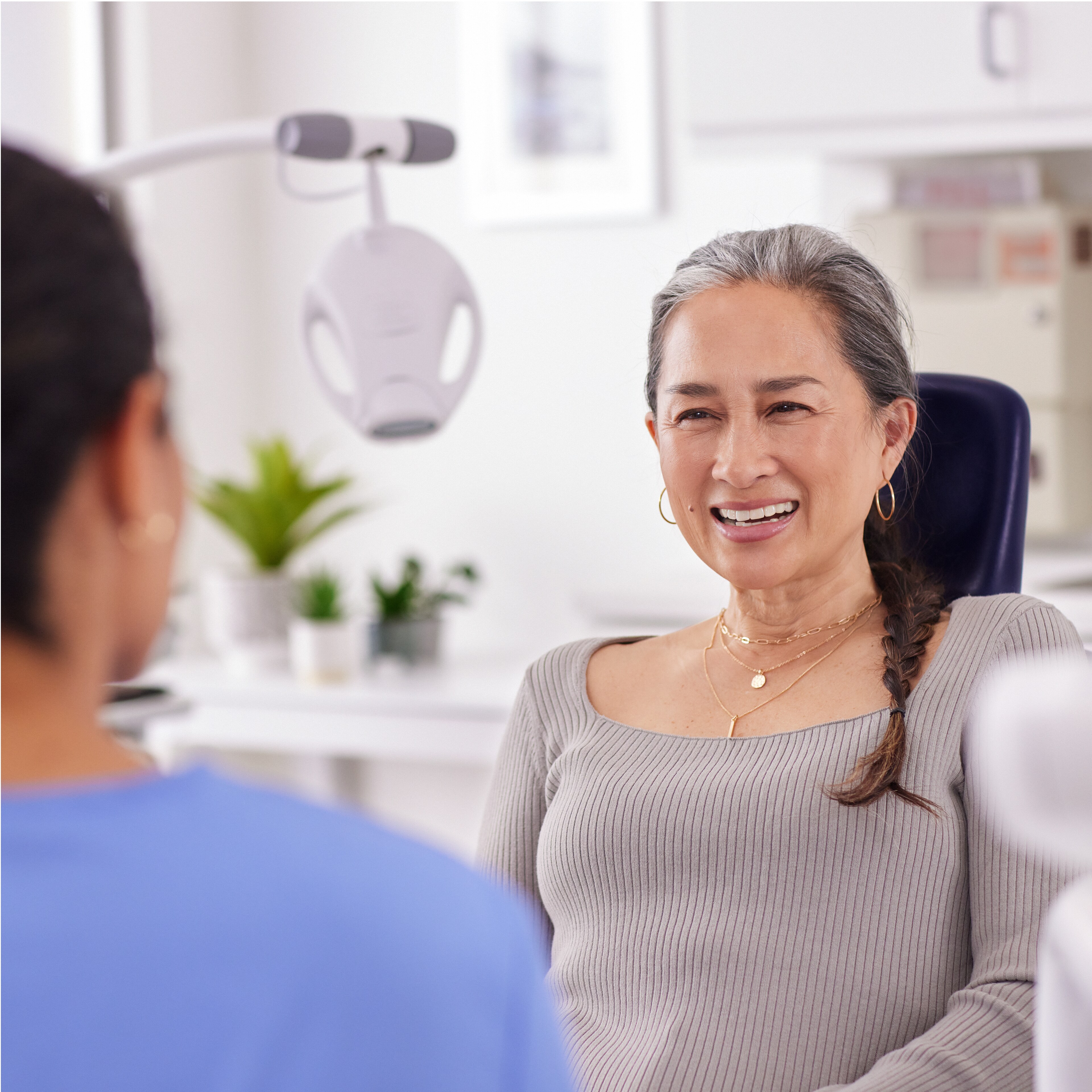 En patient som pratar med tandvårdspersonal med en Philips Zoom! WhiteSpeed-lampa i bakgrunden