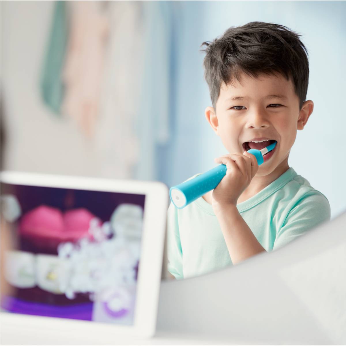 Pojke som anv&auml;nder en Sonicare For Kids-eltandborste samtidigt som han tittar i Sonicare For Kids-appen