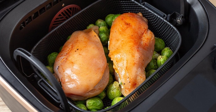 Öppna Air Cookern när brysselkålen är färdigångad och lägg kycklingbröstfiléerna på brysselkålen i korgen. 