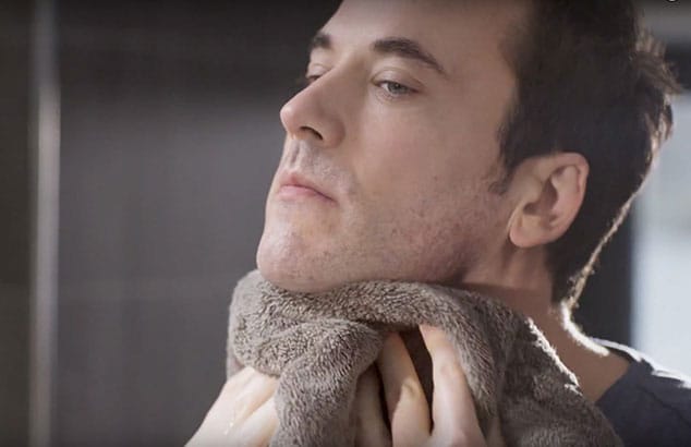 En man torkar sin hals med en handduk efter rakning.