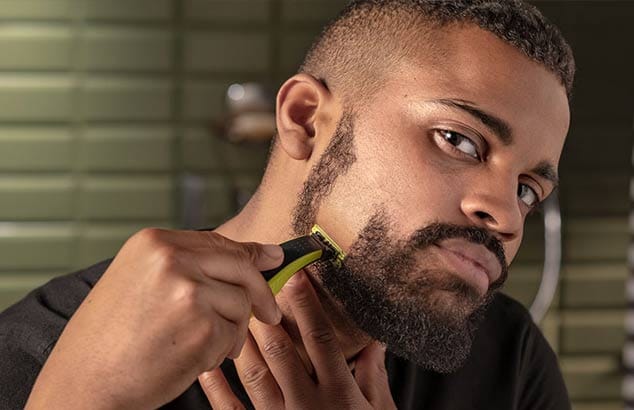 En man som har rakat i en linje på höger sida av skägget med en rakhyvel.