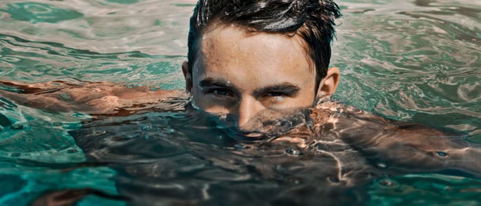 Man med brunt hår i swimmingpool med endast övre delen av ansiktet synligt.